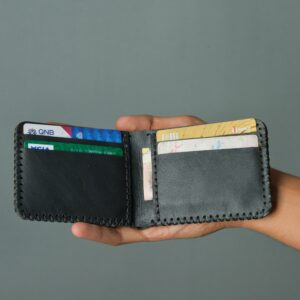 Close-up of a hand holding a leather wallet containing various cards.